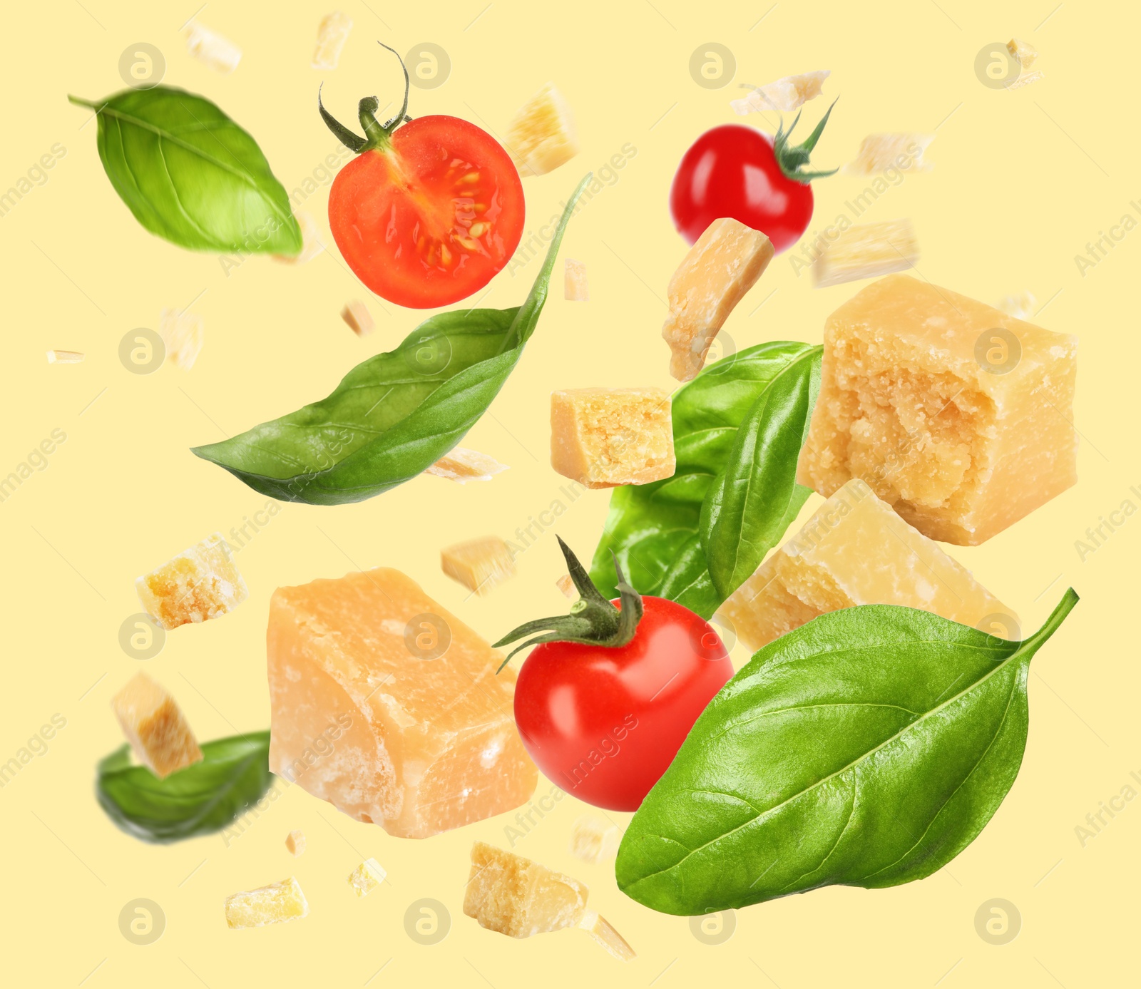 Image of Pieces of delicious parmesan, tomatoes and basil leaves falling on yellow background