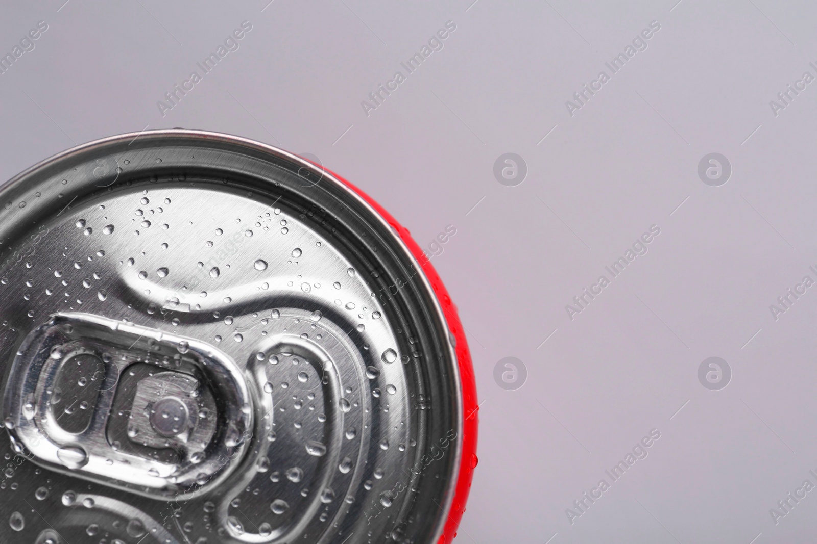 Photo of Energy drink in wet can on light grey background, top view. Space for text