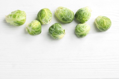 Fresh Brussels sprouts on white wooden table, flat lay. Space for text