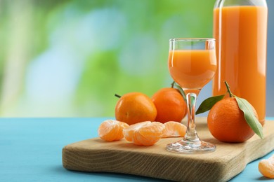 Delicious tangerine liqueur and fresh fruits on light blue wooden table, space for text