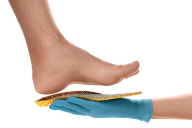 Photo of Orthopedist fitting insole on patient's foot against white background, closeup