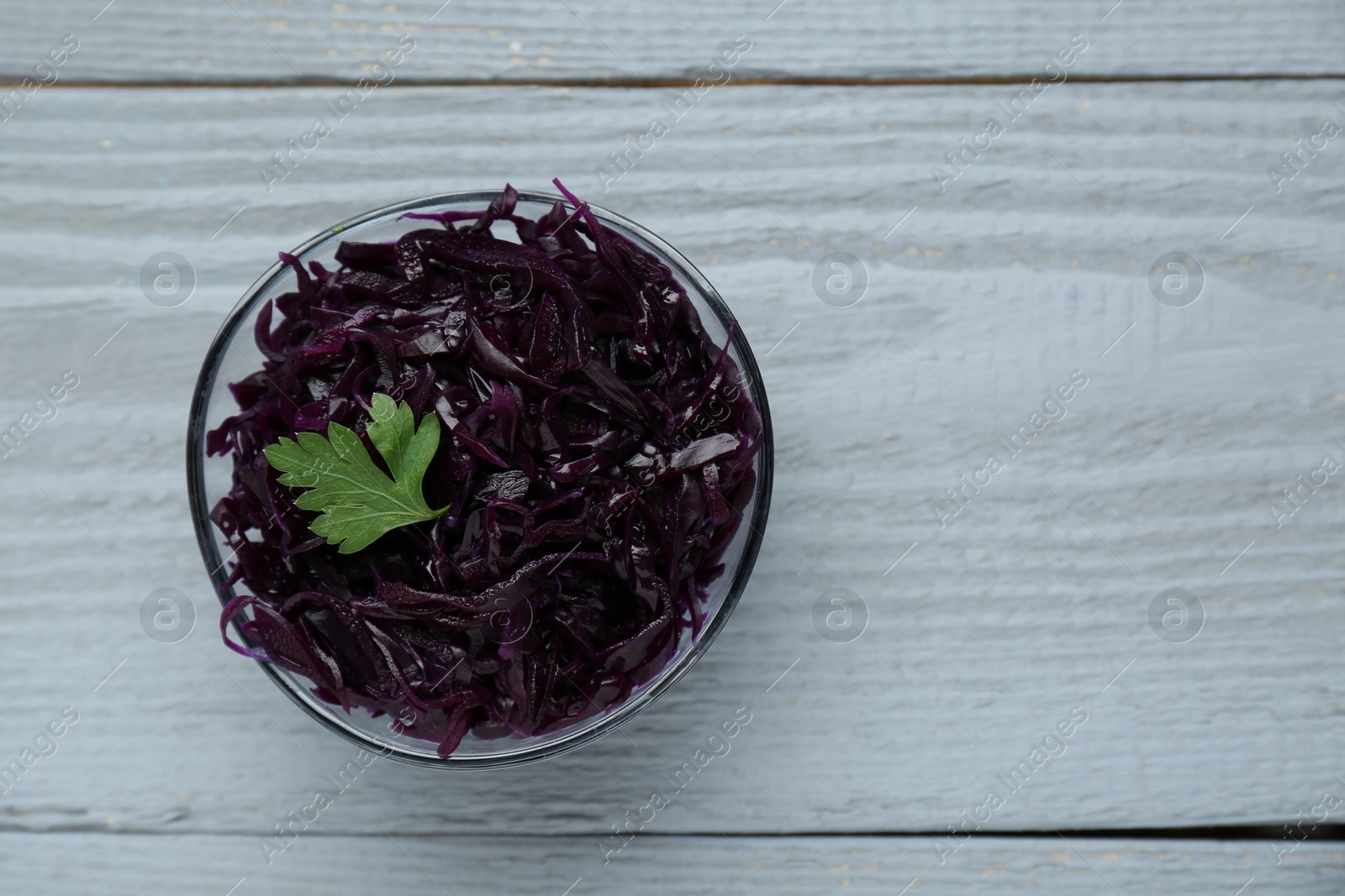 Photo of Tasty red cabbage sauerkraut with parsley on light grey wooden table, top view. Space for text