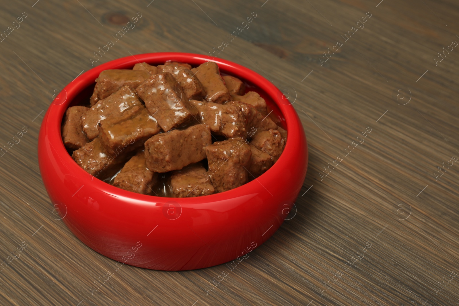 Photo of Wet pet food in feeding bowl on wooden background, space for text