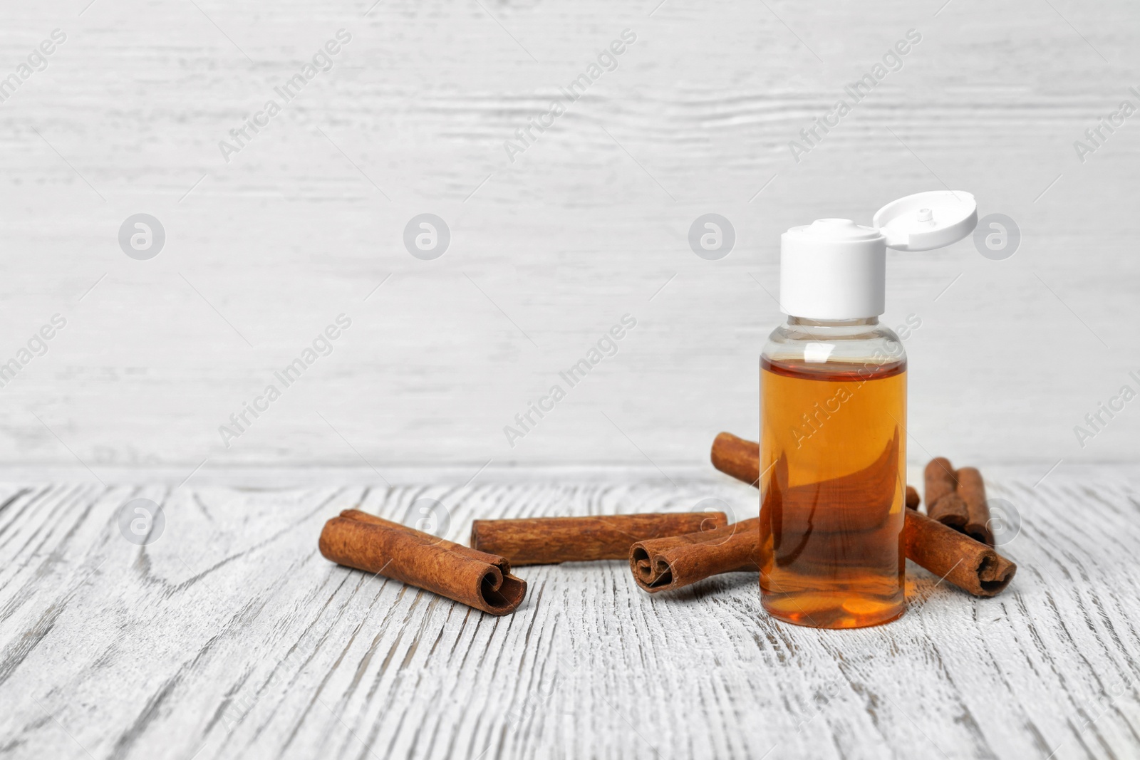 Photo of Bottle with cinnamon oil and sticks on wooden table