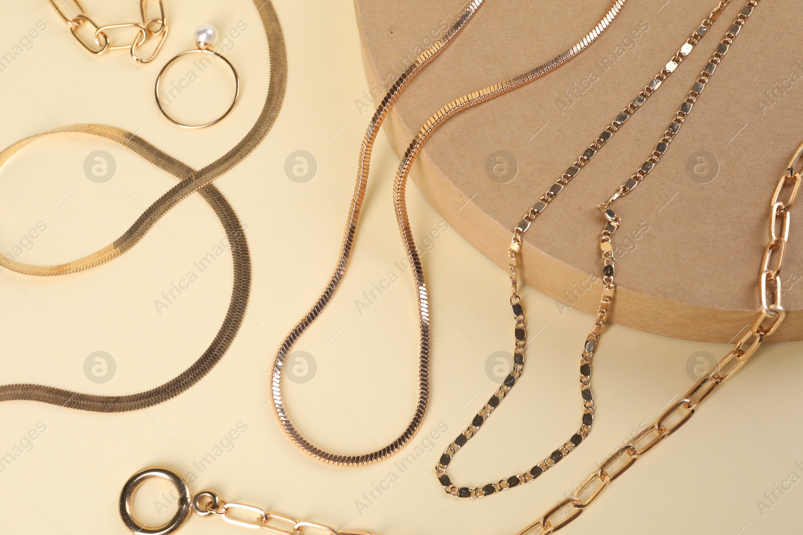 Photo of Metal chains and ring on beige background, above view. Luxury jewelry