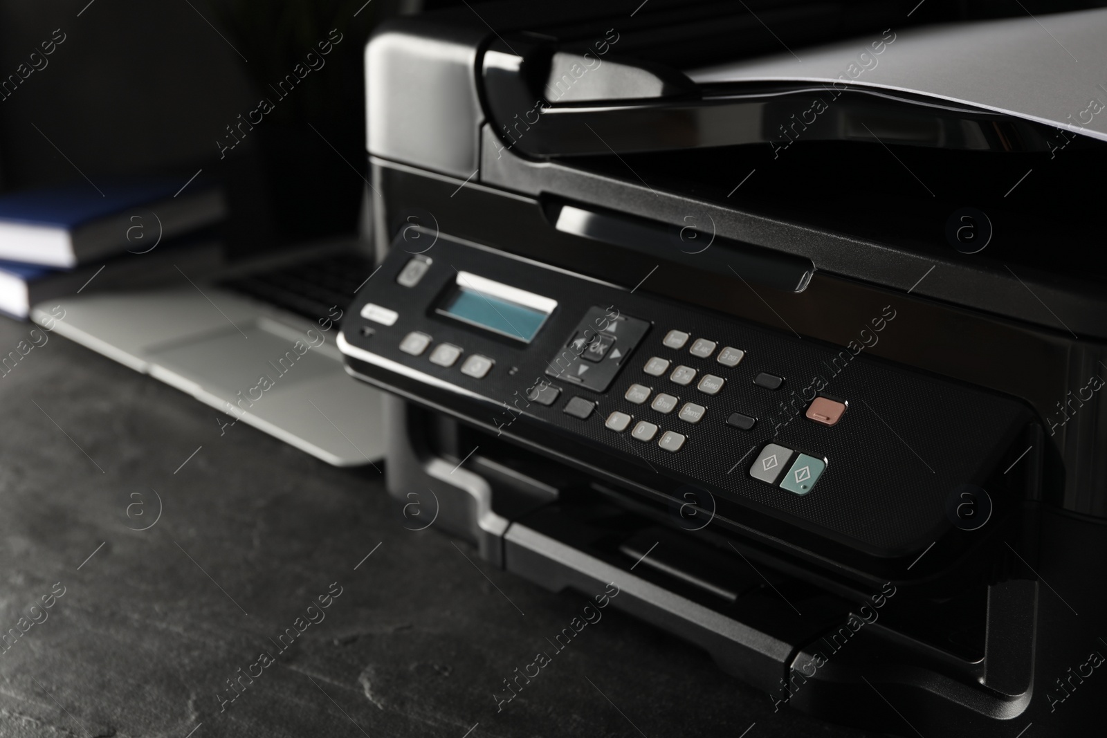 Photo of Closeup view of new modern printer with control panel on black table