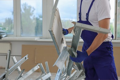 Construction worker with used building materials in room prepared for renovation, closeup