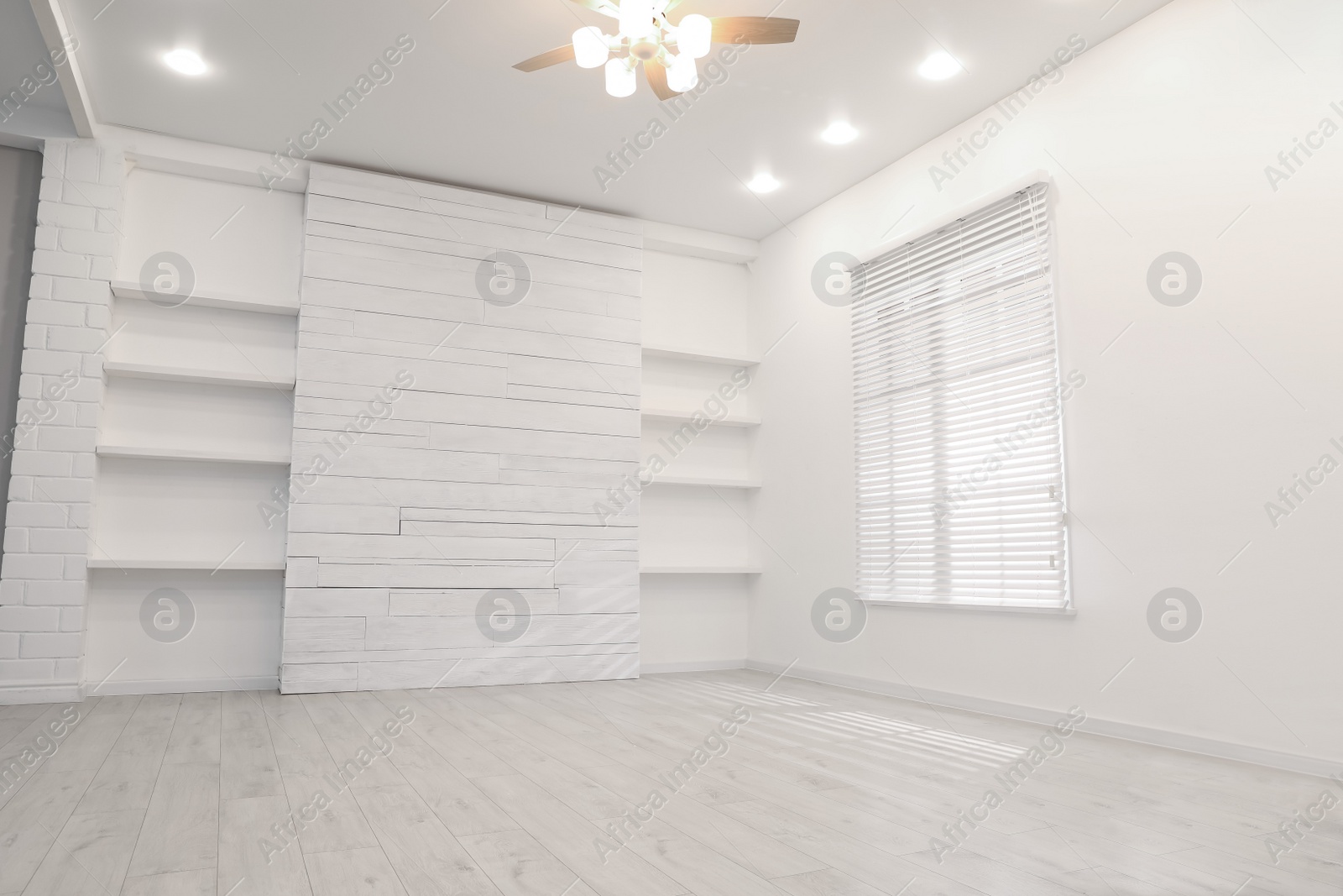 Photo of Empty room with textured wall, stylish wooden shelves and large window