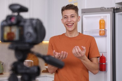 Smiling food blogger explaining something while recording video in kitchen