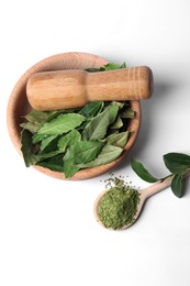 Wooden mortar and pestle with bay leaves on white background, top view