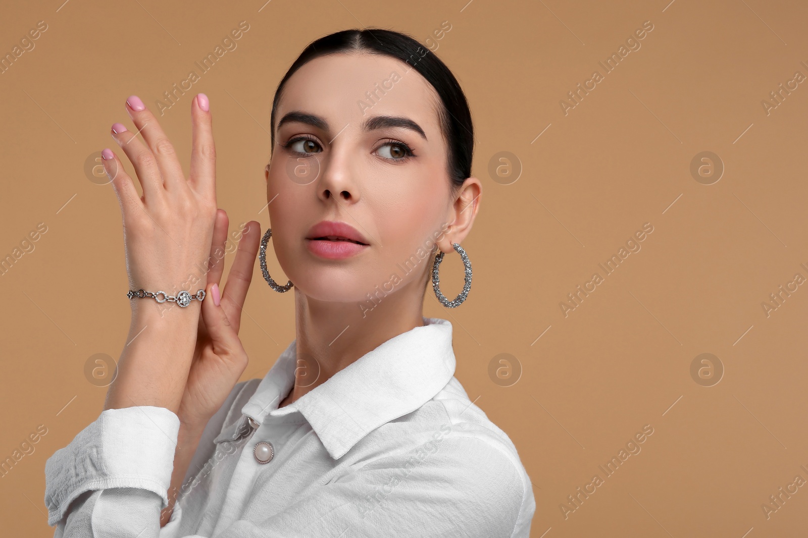 Photo of Young woman with elegant jewelry on beige background