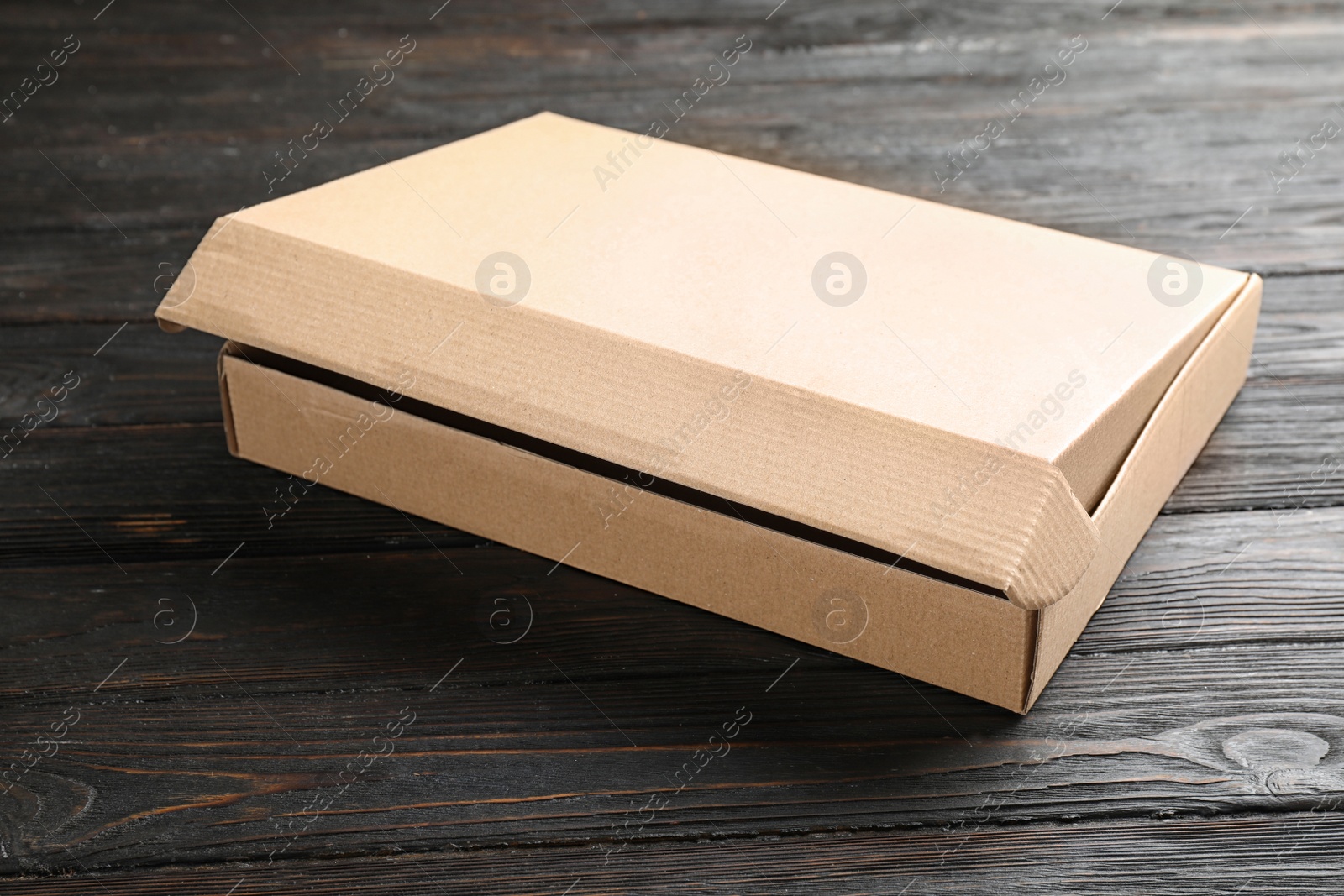 Photo of Open cardboard box on black wooden table