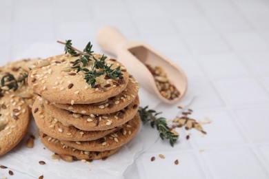 Photo of Cereal crackers with flax, sesame seeds and thyme on white tiled table, closeup. Space for text