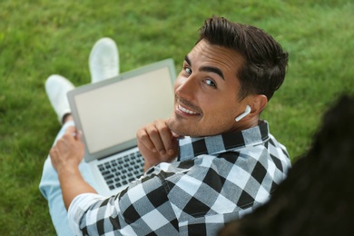 Portrait of young man with laptop outdoors. Space for design