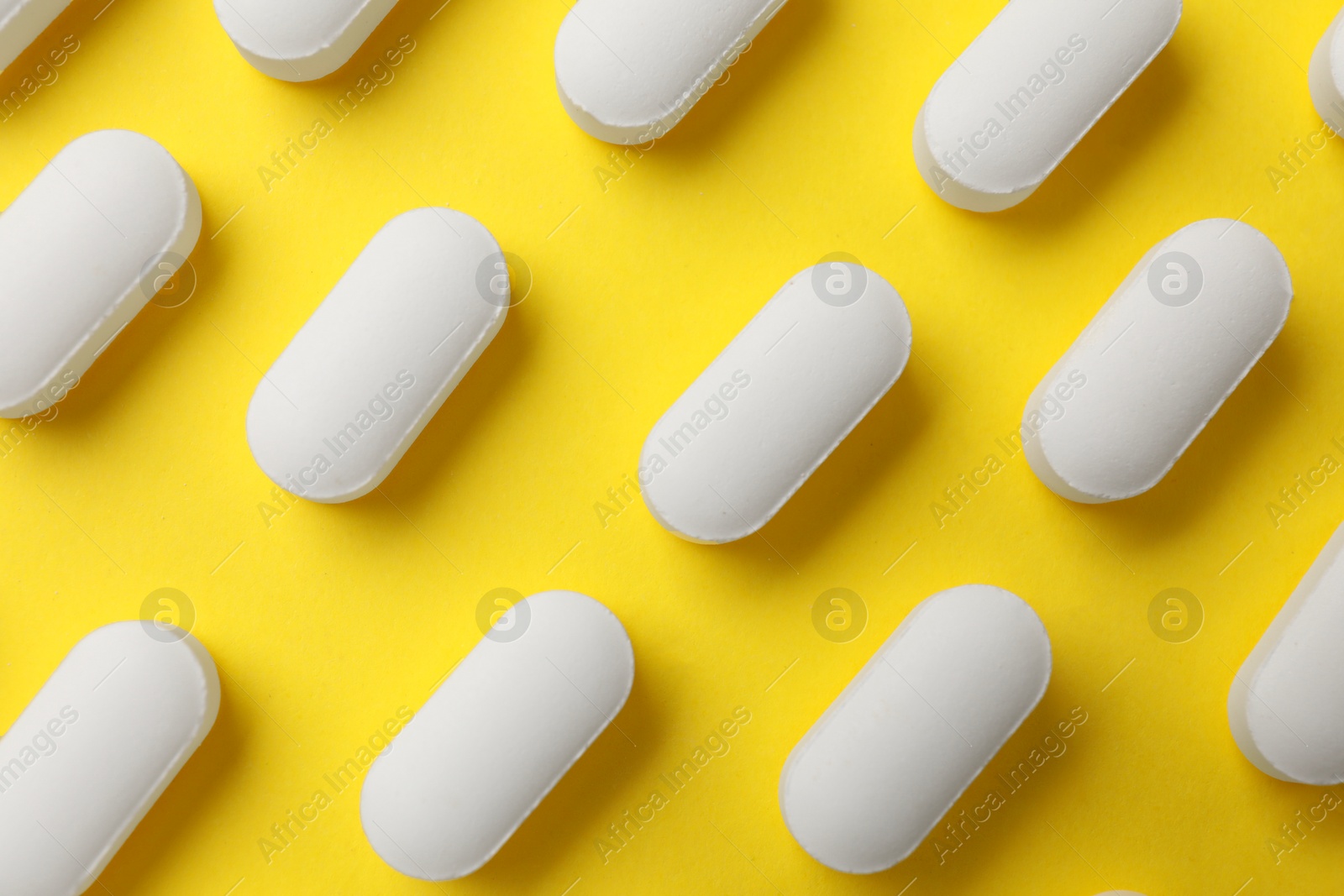 Photo of Vitamin pills on yellow background, flat lay