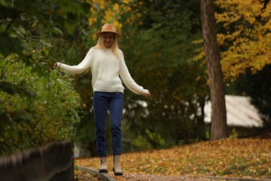 Photo of Happy woman walking in autumn park. Space for text