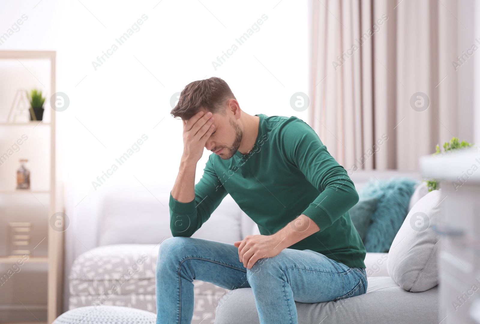 Photo of Young man suffering from headache at home