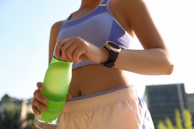 Photo of Woman with fitness tracker after training outdoors, closeup