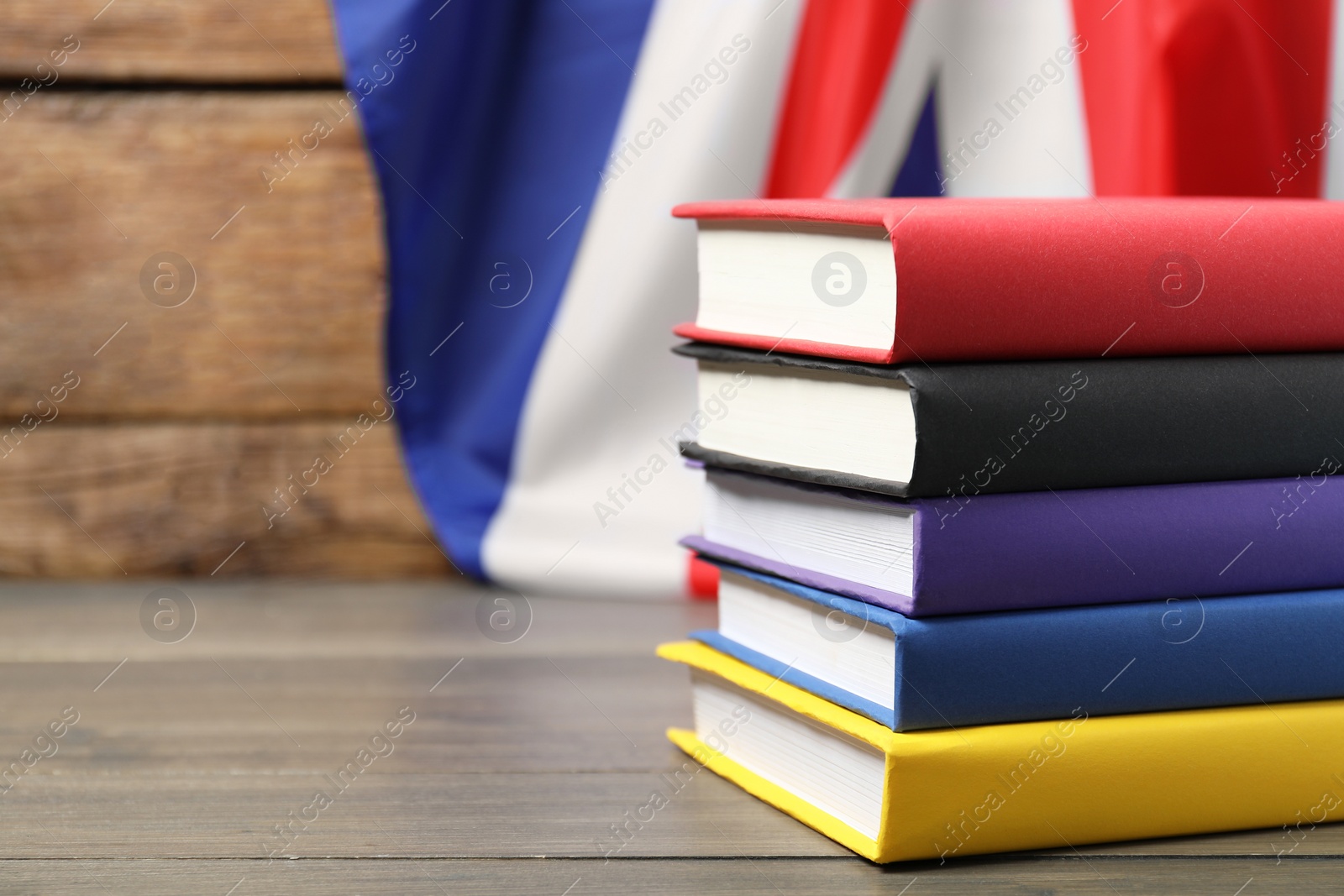 Photo of Learning foreign language. Different books on wooden table near flag of United Kingdom, space for text