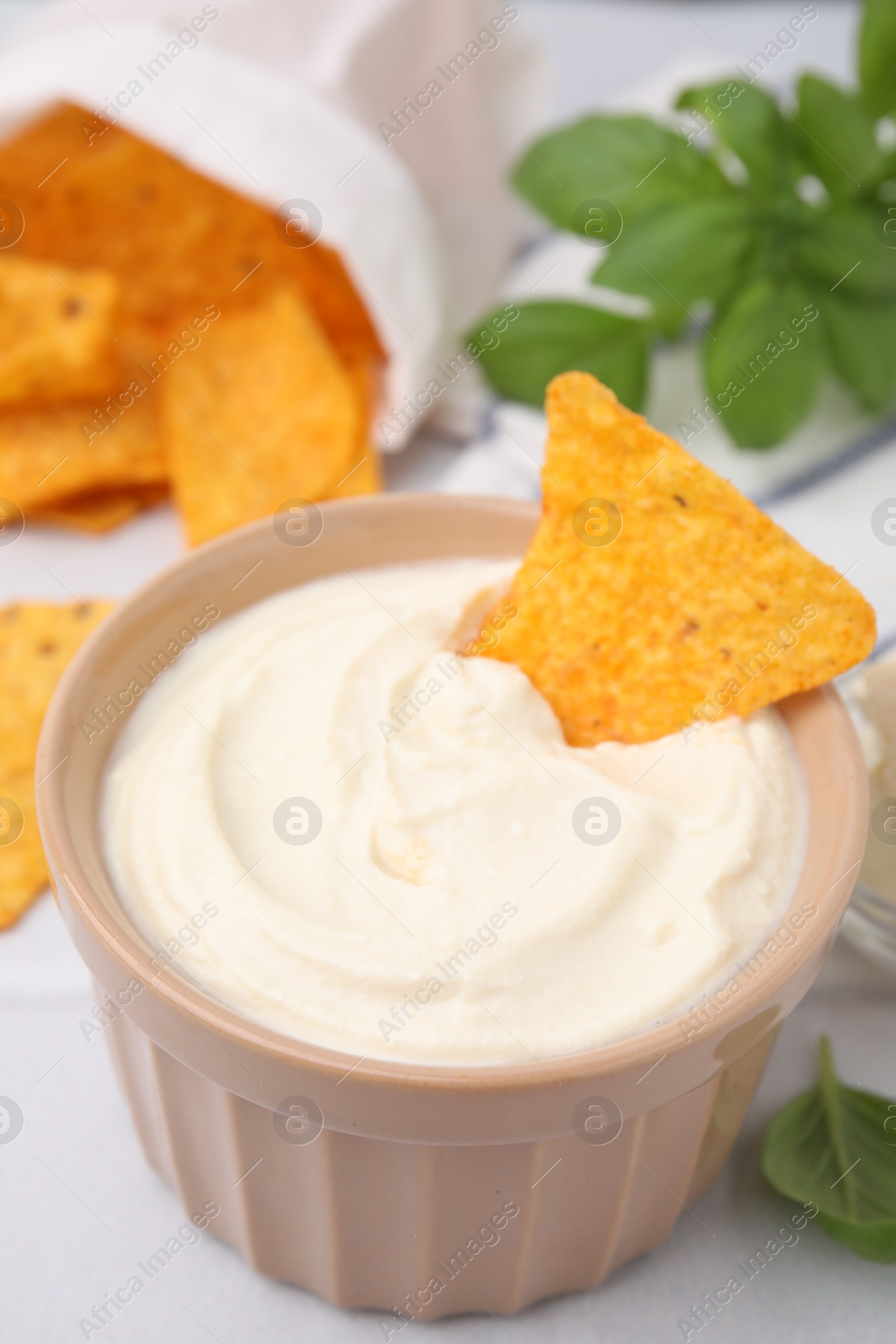 Photo of Delicious tofu sauce served with nachos chips on white table, closeup