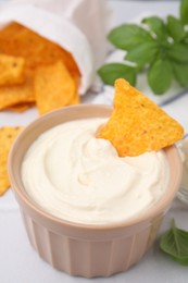 Photo of Delicious tofu sauce served with nachos chips on white table, closeup