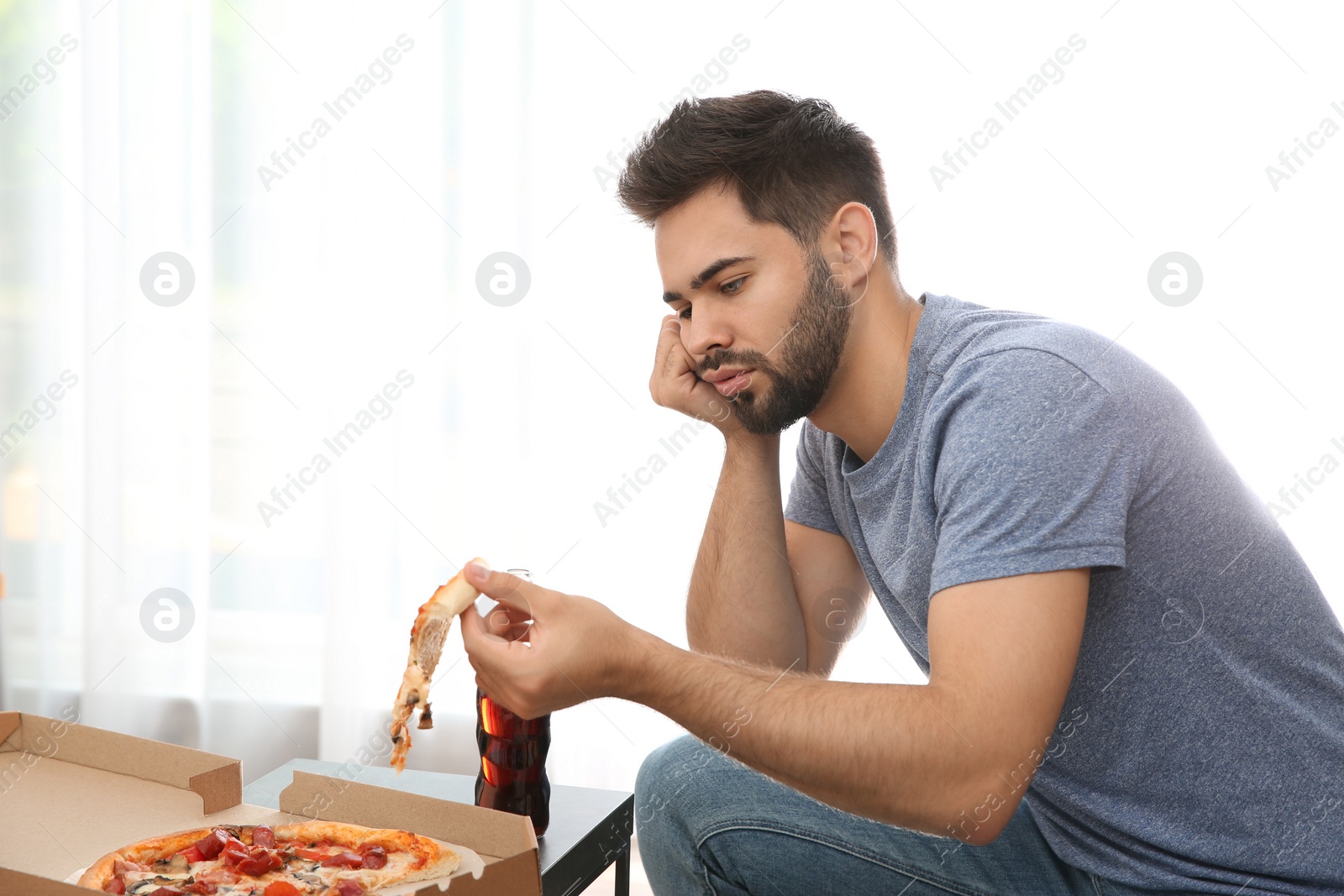 Photo of Lazy young man eating pizza at home
