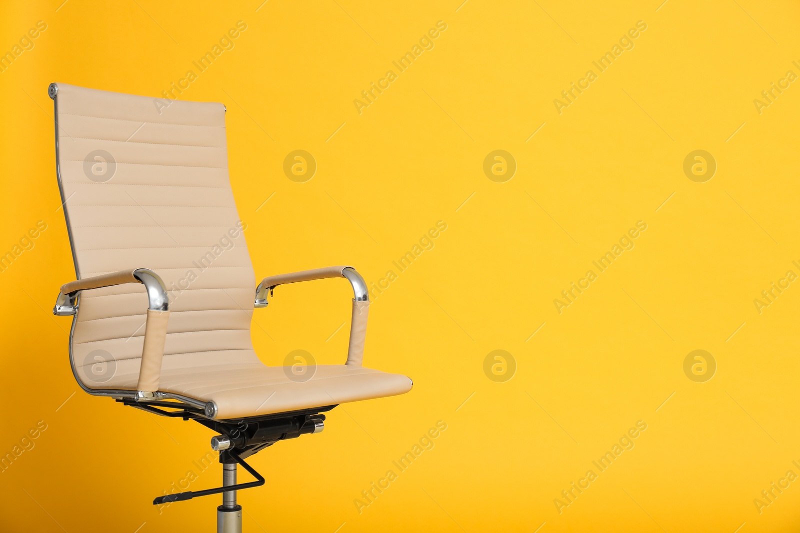 Photo of Modern office chair on yellow background. Space for text