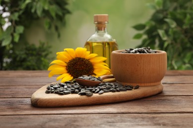 Photo of Sunflower, seeds and bottle of oil on wooden table against blurred background