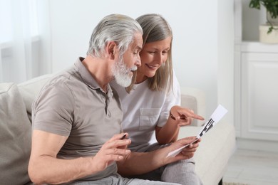 Senior couple solving crossword on sofa at home