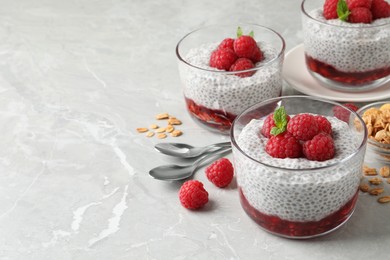 Photo of Delicious chia pudding with raspberries and mint on light marble table, space for text