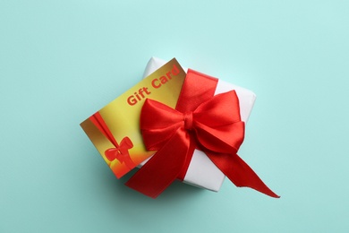 Gift card and present on light blue background, top view