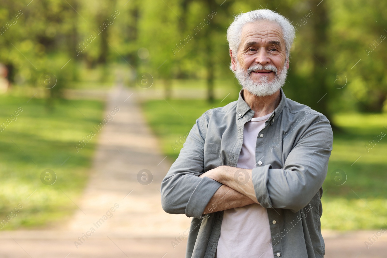 Photo of Portrait of happy grandpa with grey hair in park, space for text