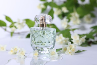 Photo of Aromatic perfume in bottle and beautiful jasmine flowers on white background