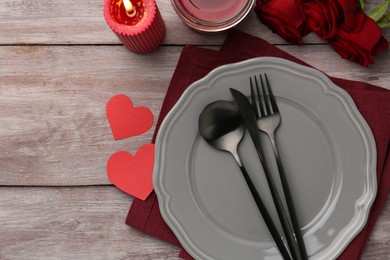 Photo of St. Valentine's day dinner. Romantic place setting with red roses, candles and decorative hearts on wooden table, flat lay. Space for text