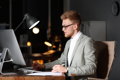 Young businessman working in office alone at night