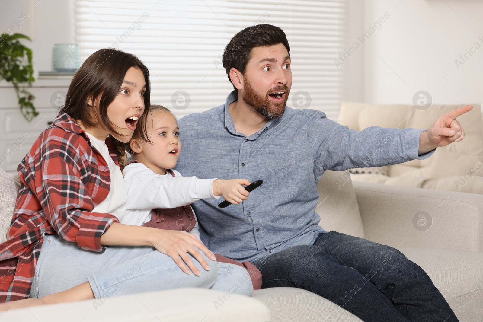 Photo of Surprised family watching TV on sofa at home