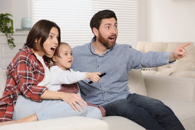 Photo of Surprised family watching TV on sofa at home
