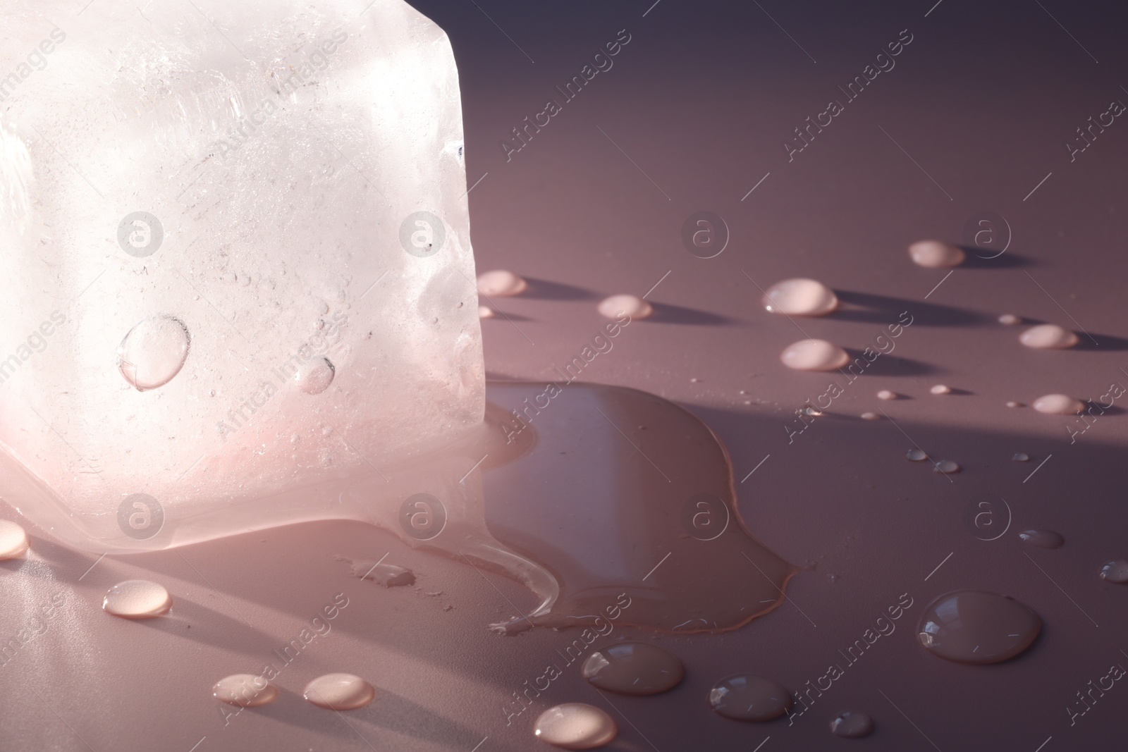 Photo of Crystal clear ice cube on pink background, closeup. Space for text
