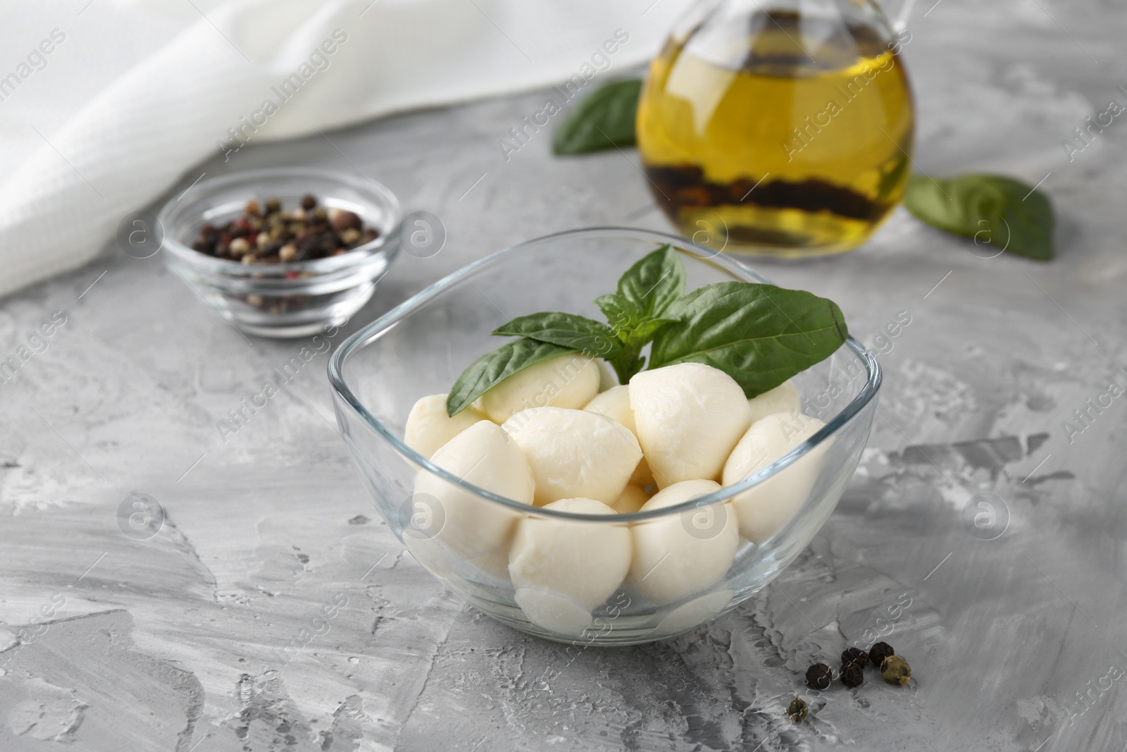 Photo of Tasty mozarella balls, basil leaves and spices on grey textured table