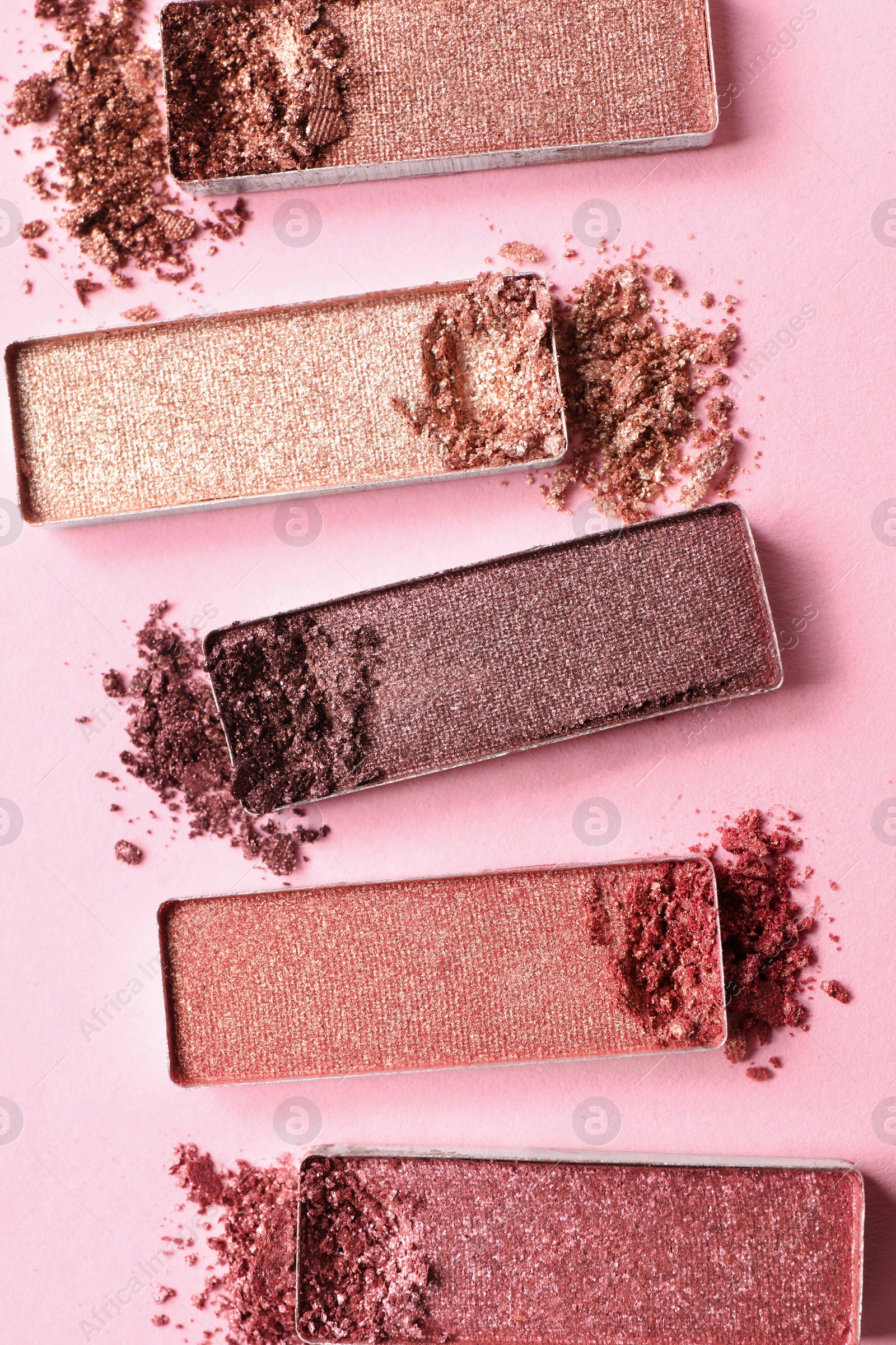 Photo of Different crushed eye shadows on pink background, flat lay. Professional makeup product