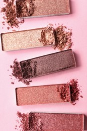 Different crushed eye shadows on pink background, flat lay. Professional makeup product
