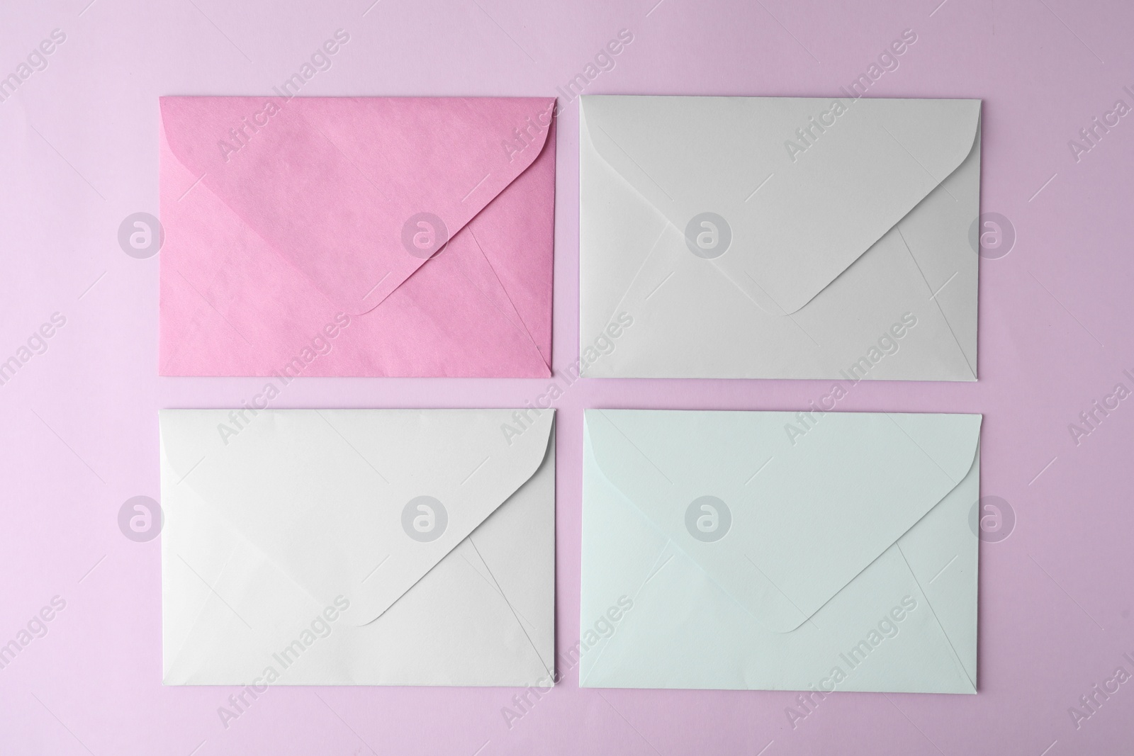 Photo of Colorful paper envelopes on pink background, flat lay