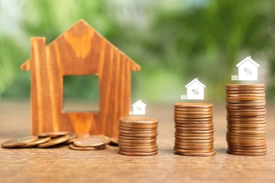 Image of Mortgage rate. Stacked coins, percent signs and wooden model of house