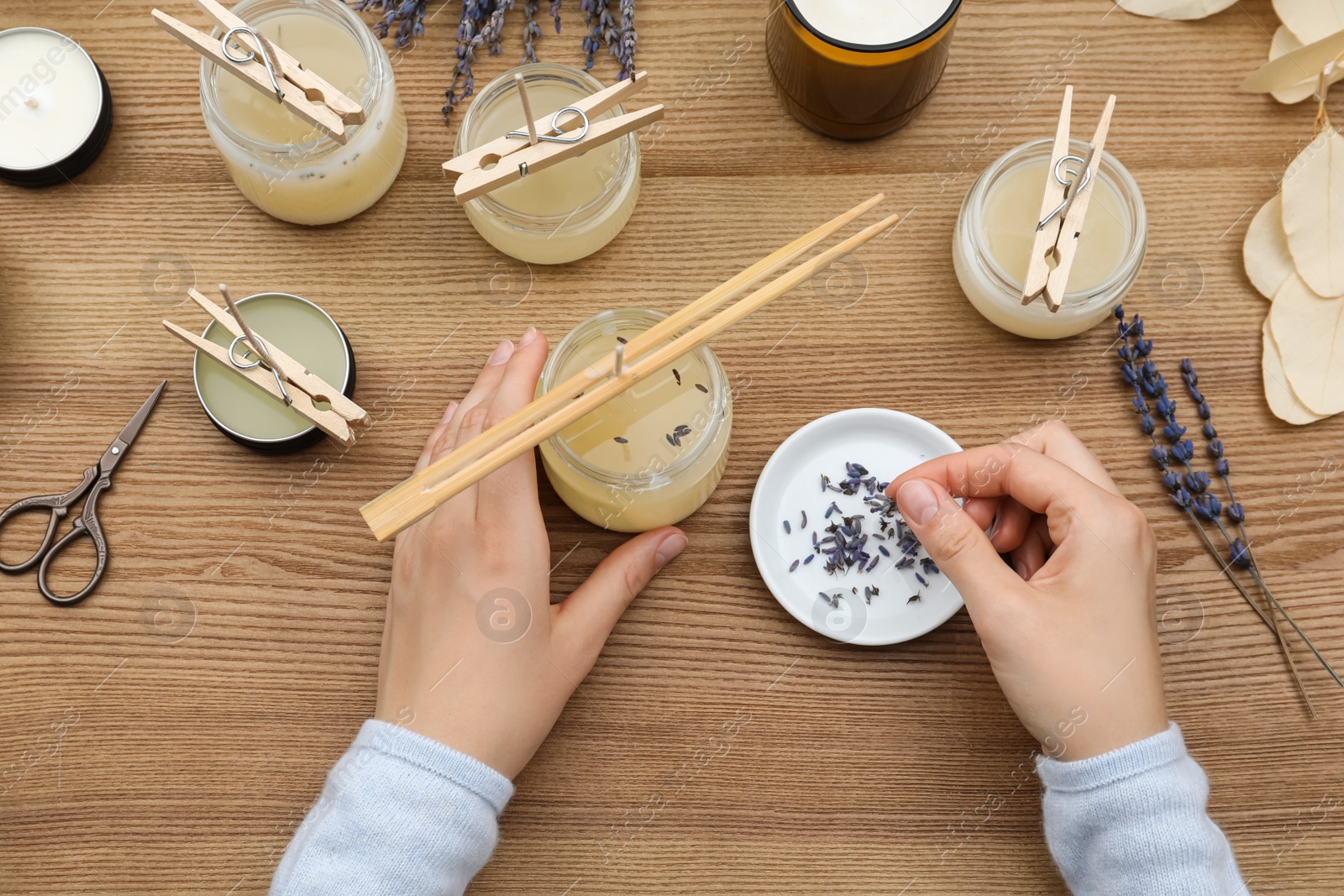 Photo of Woman making aromatic candles at wooden table, top view