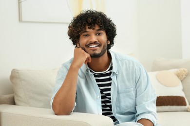 Portrait of handsome smiling man on sofa indoors