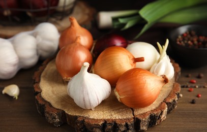 Photo of Fresh onion bulbs and garlic on wooden table