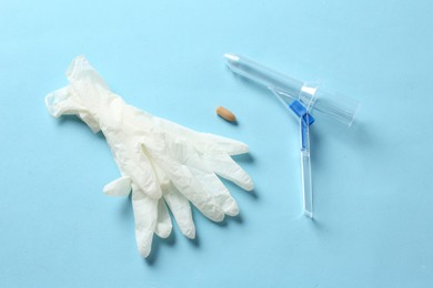 Photo of Anoscope, suppository and rubber gloves on light blue background, flat lay. Hemorrhoid treatment