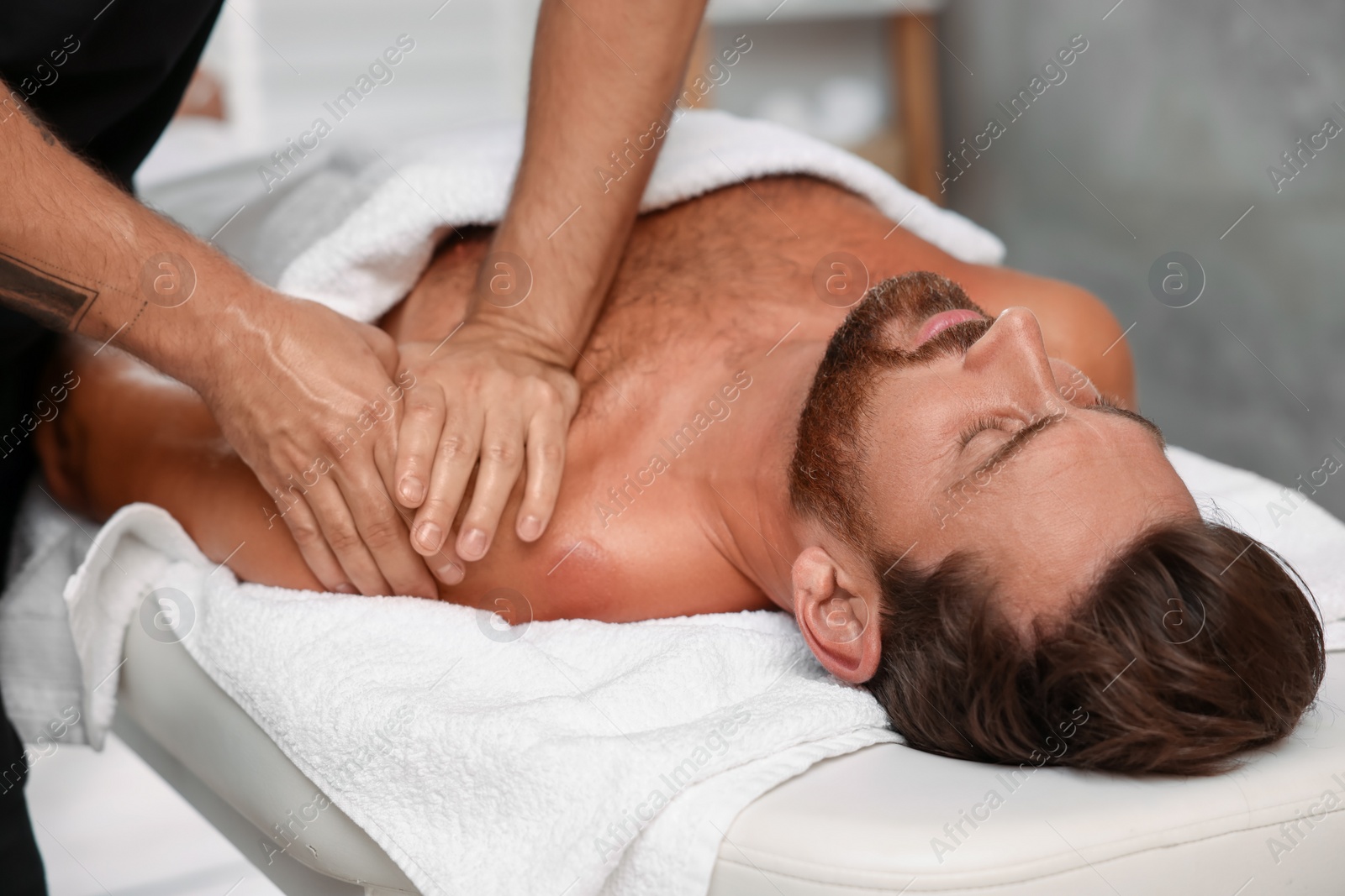 Photo of Man receiving professional massage on couch in spa salon