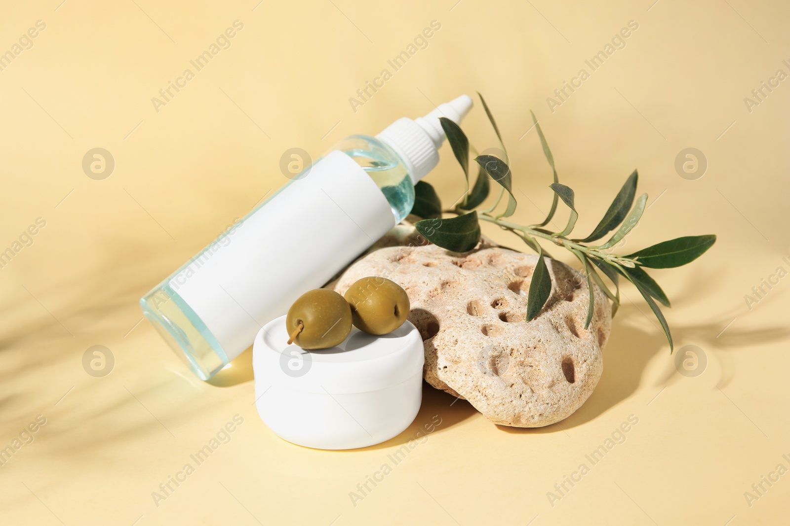 Photo of Cosmetic products and olives on beige background