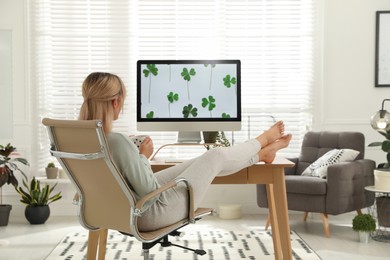 Photo of Woman with cup of tea at table in light room. Home office